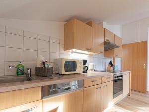 a kitchen with wooden cabinets and a microwave at Apartment Alpenchalets - ZSE202 by Interhome in Zell am See