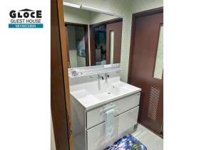 a bathroom with a white sink and a mirror at GLOCE PORT SIDE HOUSE l 砂山ビーチ近くのオーシャンビューバルコニーハウスを貸切 長期滞在向け BBQ可 in Nishibaru