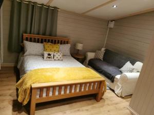 a bedroom with a large bed and a couch at The Cwtch Knighton Powys Hot Tub included in Knighton