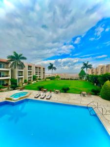 a pool with chairs and palm trees in a resort at Panacea Suites Hotel in Borg El Arab