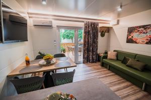 een woonkamer met een groene bank en een tafel bij Premium Mobile Homes with thermal riviera tickets in Čatež ob Savi