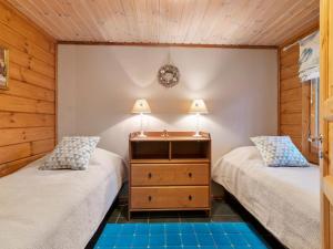two twin beds in a room with wood paneling at Holiday Home Lomaylläs maja- palovaarankaarre 6 a by Interhome in Ylläsjärvi
