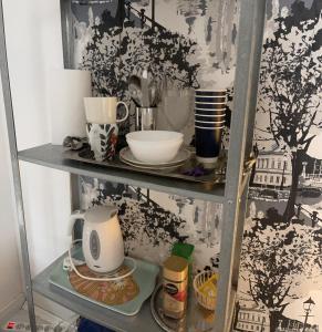 a shelf with a tea kettle and dishes on it at Pieni huone 1 km jokirannasta in Turku