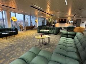 a living room with green couches and tables and windows at Hôtel Lodge In Paris 13 in Paris