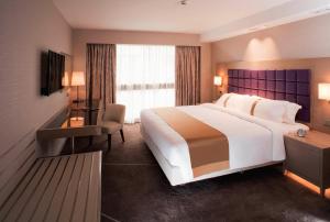 um quarto de hotel com uma cama grande e uma secretária em Holiday Inn Golden Mile, an IHG Hotel em Hong Kong