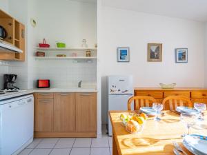 una cocina con una mesa de madera con cuencos de fruta. en Apartment Jardins de Pontaillac-1 by Interhome en Pontaillac