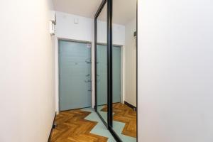 korytarz ze szklanymi drzwiami i drewnianą podłogą w obiekcie SuperApart Tarchomińska apt 24 w Warszawie