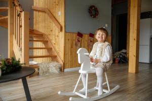 une petite fille assise sur une chaise dans une pièce dans l'établissement Domy Morskie Family Resort, à Jantar 130 autres photos