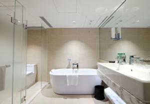 uma casa de banho com 2 lavatórios, uma banheira e um chuveiro em Holiday Inn Golden Mile, an IHG Hotel em Hong Kong