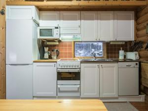 La cuisine est équipée de placards blancs et d'un réfrigérateur blanc. dans l'établissement Holiday Home Rannantupa by Interhome, à Hersala