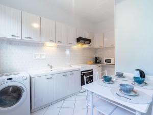 ロワイヤンにあるApartment Jonain by Interhomeの白いキッチン(洗濯機、テーブル付)