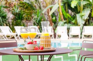 a table with two glasses of orange juice and strawberries at Aspasios Garden Apartments in Barcelona
