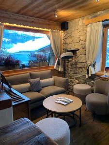 een woonkamer met een bank, een tafel en een piano bij Les Chalets de La Griyotire in Praz-sur-Arly