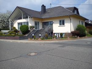 ein großes weißes Haus mit einer Treppe und einer Veranda in der Unterkunft Ferienwohnung Schmitz in Anschau