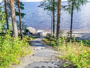 un chemin à côté d'une masse d'eau plantée d'arbres dans l'établissement Holiday Home Kolinpilvi by Interhome, à Kolinkylä