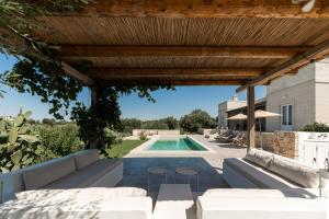 a backyard with a swimming pool and a wooden pergola at Villa Margareta in Ostuni