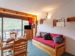 a living room with a red couch and a balcony at Apartment Baikonour-4 by Interhome in Le Corbier