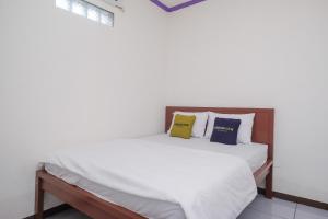 a bedroom with a bed with white sheets and pillows at Urbanview Syariah Zidney 3 Salatiga by RedDoorz in Salatiga