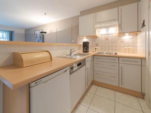eine Küche mit weißen Schränken und einer Spüle in der Unterkunft Apartment De vakantieduinen aan zee by Interhome in Mispelburg