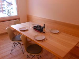 Apartment Armina by Interhome في زيرمات: طاولة خشبية مع كراسي وزجاجة من النبيذ