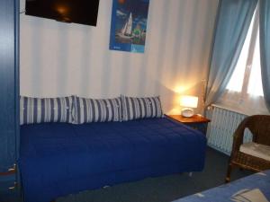 a blue couch in a room with a window at Hôtel LeRichelieu, Le Havre Centre-Ville in Le Havre