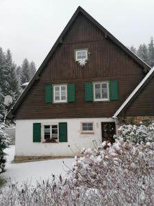 a house with green shutters and a snow covered yard at Ferienhaus am Wald in Bad Elster