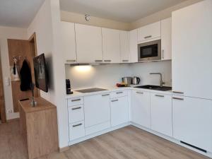 a white kitchen with white cabinets and a microwave at Apartment Alpenschnucke Home by Interhome in See
