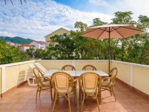 una mesa y sillas en un balcón con sombrilla en Holiday Home Koka by Interhome, en Rab