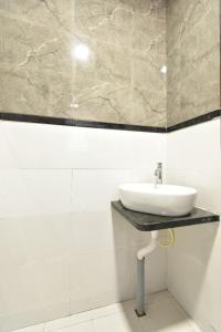 a white bathroom with a sink on a wall at Hotel Ashirwad, Solapur in Solapur