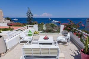 a patio with white chairs and a table and the ocean at Villa Sea Rose in Lipari