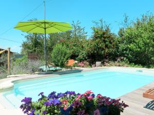 una piscina con una sombrilla verde y flores en Apartment Livella - MZO100 by Interhome, en Belvedere Langhe