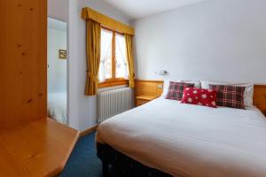 1 dormitorio con 1 cama blanca grande con almohadas rojas en Residence Sci Sport en Bormio