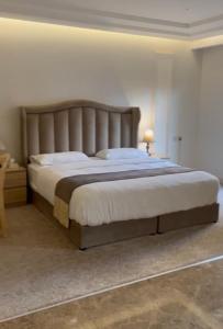 1 dormitorio con 1 cama grande con sábanas blancas en راحتي هوم, en Al Rass