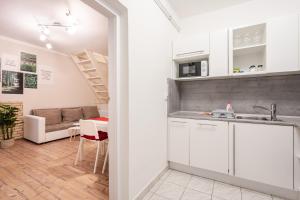 Una cocina con gabinetes blancos y una sala de estar. en Zensen Nest Apartment, en Budapest 15 fotos más