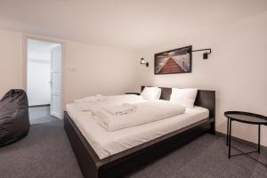 a bedroom with a large white bed and a chair at Zensen Nest Apartment in Budapest