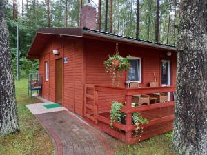 eine kleine rote Hütte im Wald mit einem Baum in der Unterkunft Domek letniskowy nad jeziorem w Gołdapi, Wczasowa72 in Goldap