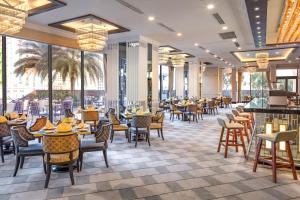 a restaurant with tables and chairs and large windows at Meliá Vinpearl Nha Trang Empire in Nha Trang