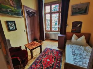 um quarto com uma cama, uma mesa e uma janela em Hummel Hostel - Historische Stadtvilla mit Garten em Weimar