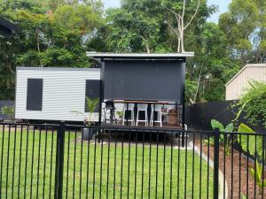 a tiny house with a black roof on a fence at Haven Guesthouse in Holloways Beach