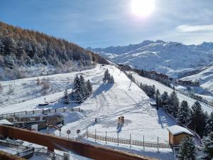 a snow covered ski slope with people skiing on it at Apartment Les Burons-3 by Interhome in Les Menuires