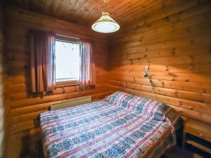 ein Schlafzimmer mit einem Bett in einer Blockhütte in der Unterkunft Holiday Home Pihatupa 2 by Interhome in Kuusamo