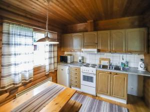 eine Küche mit Holzschränken und einem weißen Herd mit Backofen in der Unterkunft Holiday Home Pihatupa 2 by Interhome in Kuusamo