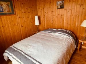 Bett in einem Holzzimmer mit zwei Lampen in der Unterkunft Chalet Seravalle by Interhome in Les Crosets
