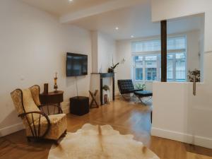 ein Wohnzimmer mit einem TV, einem Sofa und einem Stuhl in der Unterkunft Holiday Home Historical and spacious Villa Anaïs by Interhome in Blankenberge