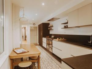 eine Küche mit weißen Schränken und einem Holztisch in der Unterkunft Holiday Home Historical and spacious Villa Anaïs by Interhome in Blankenberge