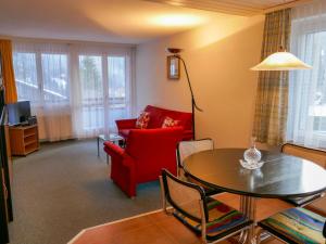 een woonkamer met een rode bank en een tafel bij Apartment Chalet Wyssefluh by Interhome in Grindelwald