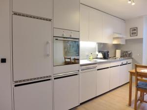 una cucina bianca con armadi bianchi e tavolo di Apartment Bieri-Haus by Interhome a Unterseen