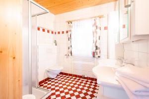 a bathroom with a checkered floor and a toilet and sink at Ahornhütte in Schladming