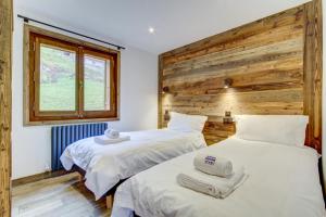 two beds in a room with a wooden wall at Ruisseau One Apartment -Snow and Trek Montriond in Montriond