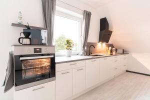 a kitchen with white cabinets and an oven at Ferienwohnung 140 qm OstfrieslandNordsee für 1-6 Personen - Südbrookmerland in Südbrookmerland